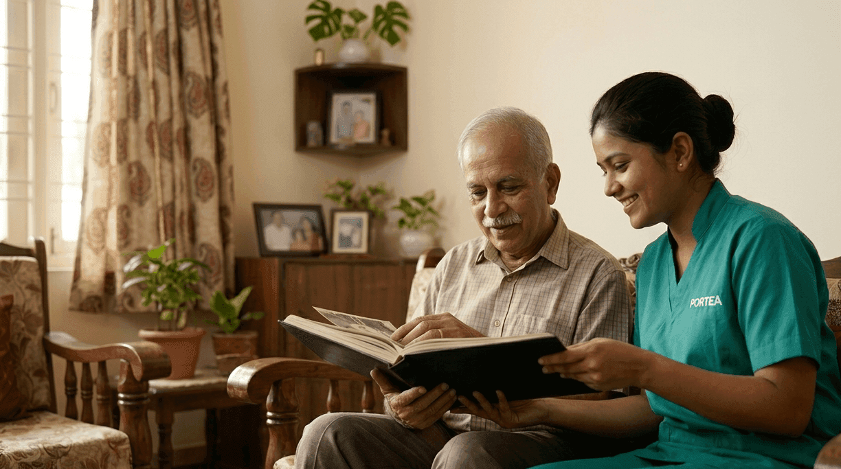 A Portea caregiver looking through a photo album with an elderly man at home